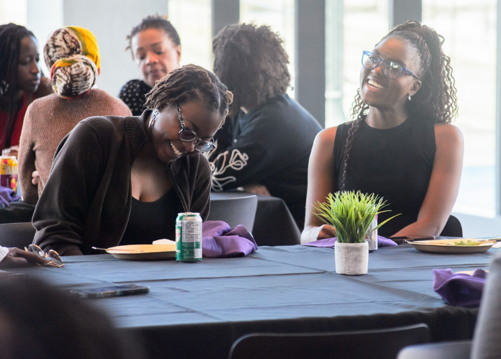 Two Black staff members laughing together while sitting at a table