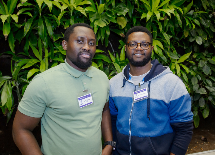 Two Western BLUE students posing for a photo in front of a green plant wall
