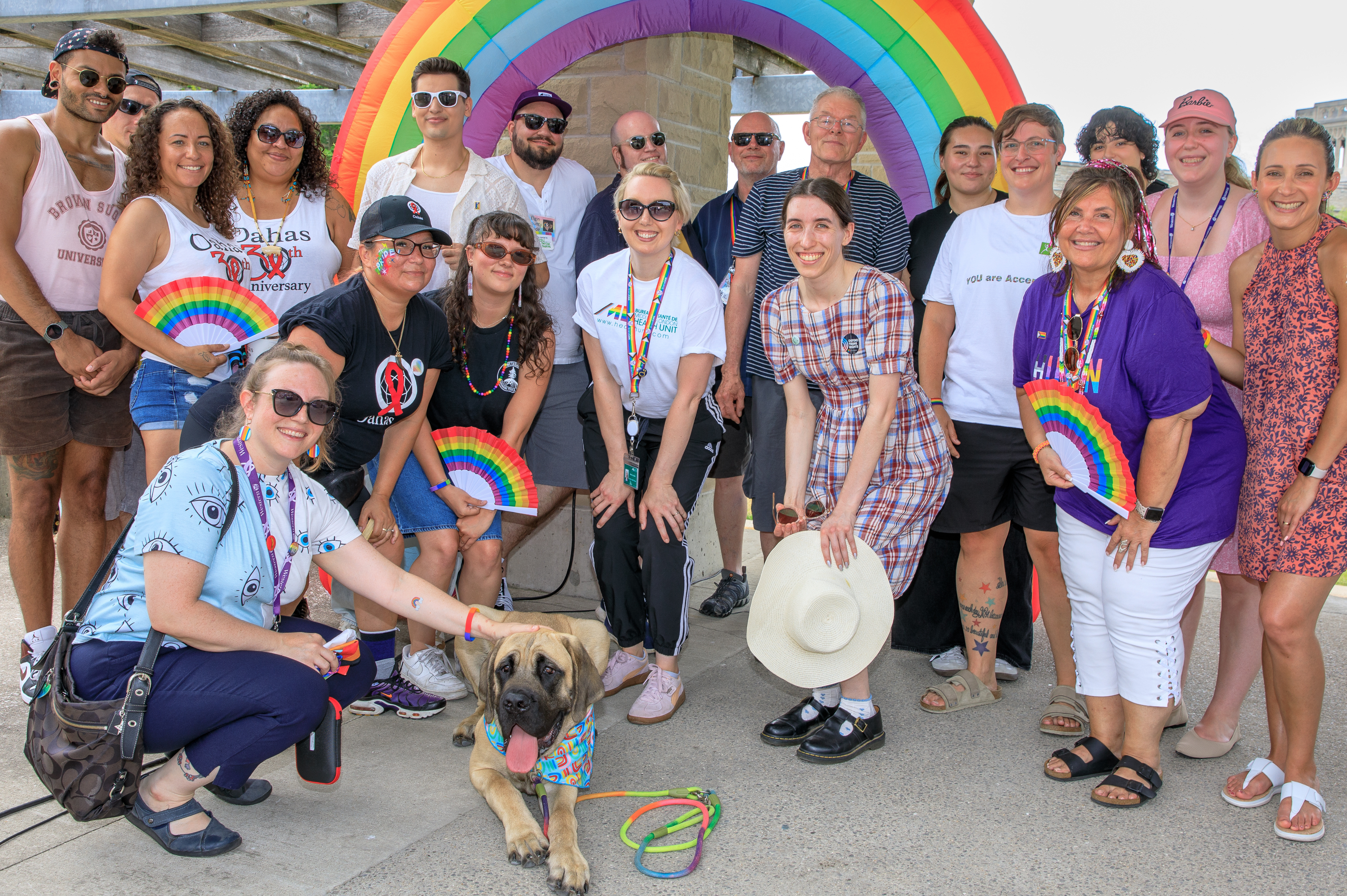 A group of people pose in front of a rainbow for Pride on Concrete Beach.