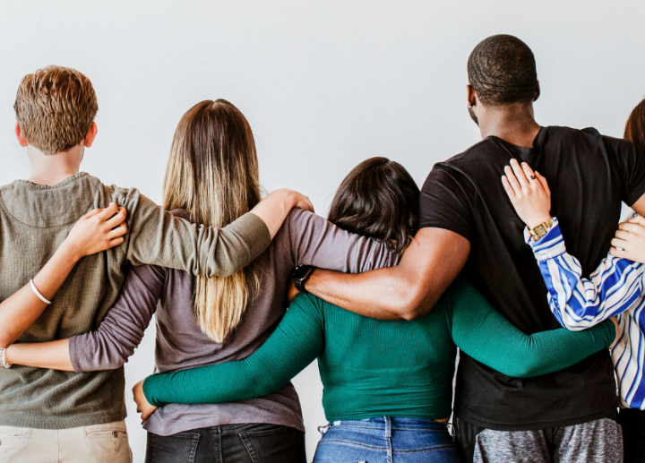 Diverse people hugging from behind against a grey backdrop