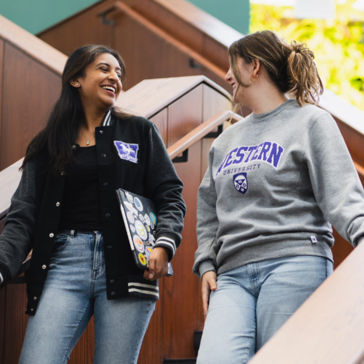 Two students walking down a staircase, smiling