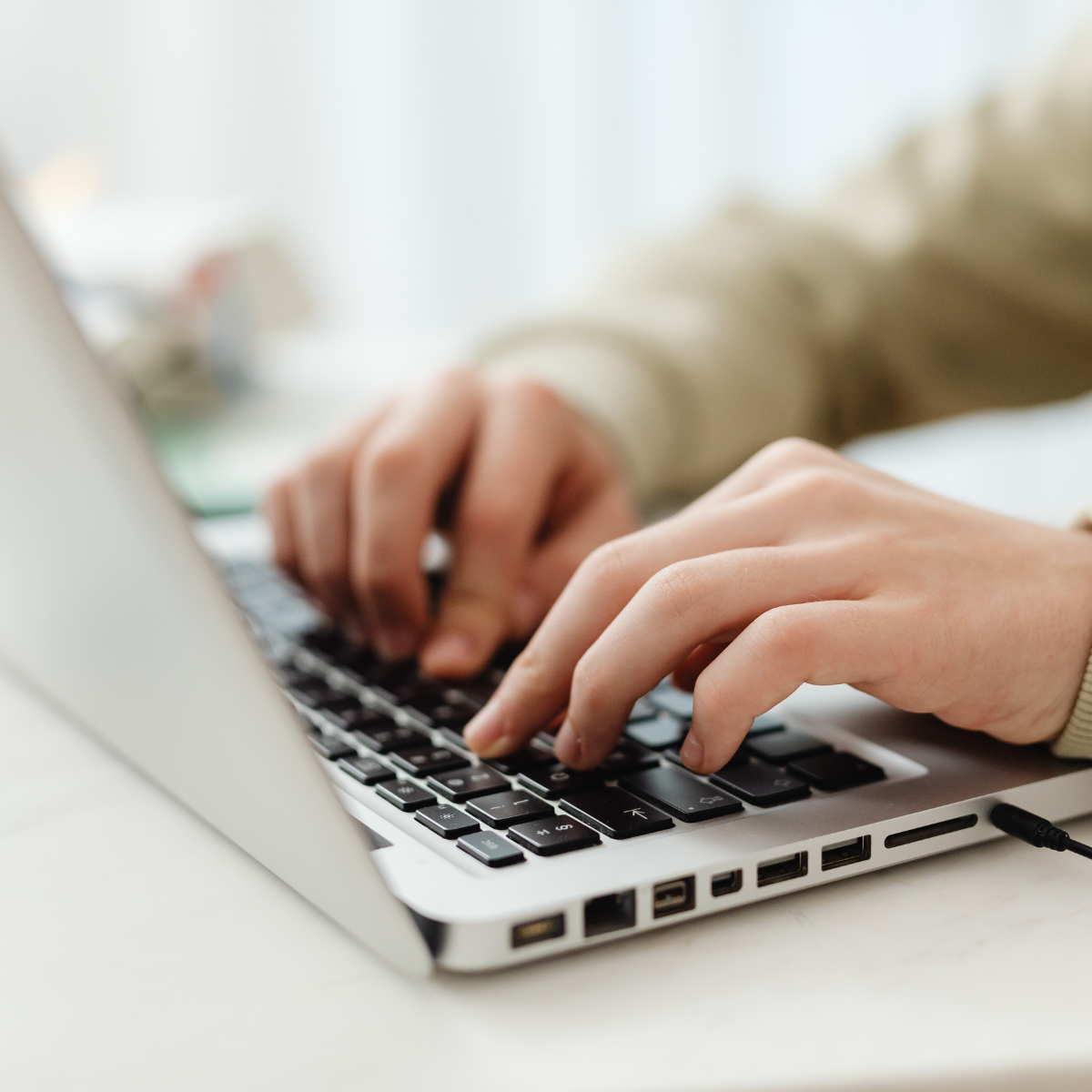 Person typing on a computer with a zoom in on their hands